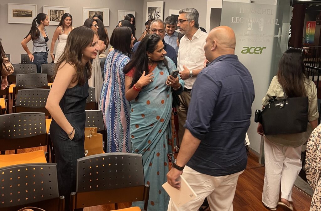 Guests mingling and discussing the notHERE exhibition photographs after the talk at Museo Camera