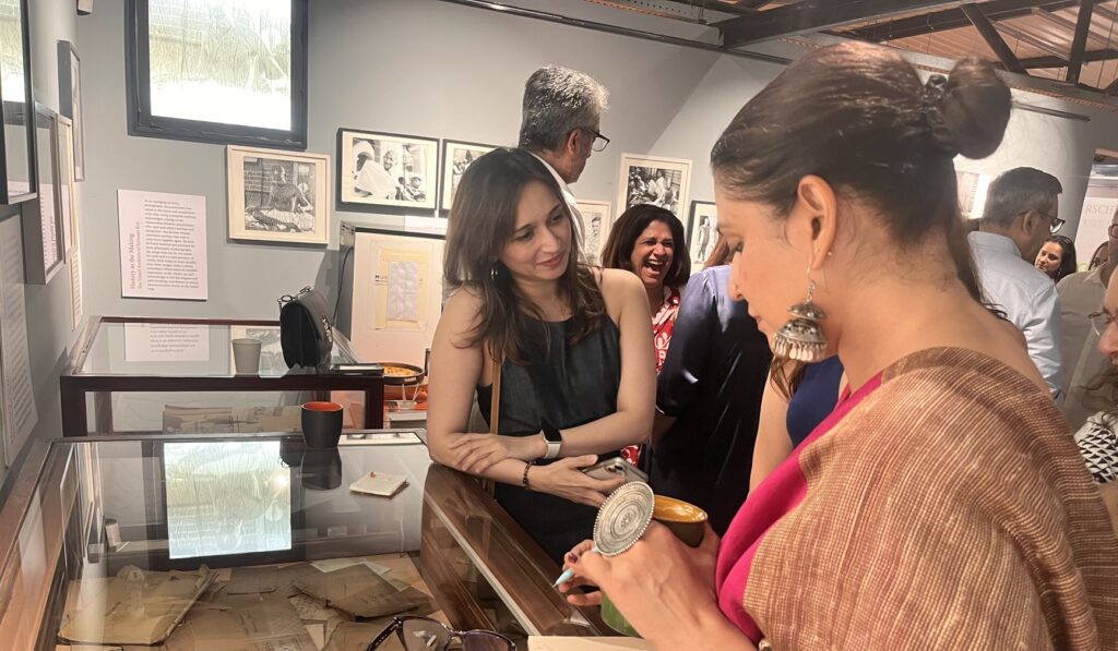 Shriti Tyagi signing a copy of notHERE for a guest at Museo Camera, surrounded by smiling attendees