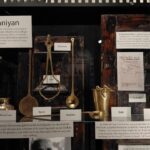 Wide shot of the brassware shelf (sarsi, jharni, kalchis, balti, keyring) at the Ghar Ki Kahaniyan installation at Museo Camera, by Camerawaali