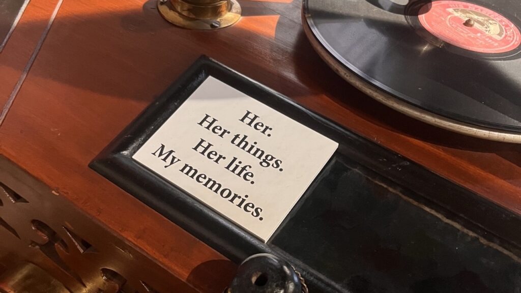 A small plaque reading "Her. Her things. Her life. My memories." displayed beside an antique gramophone record
